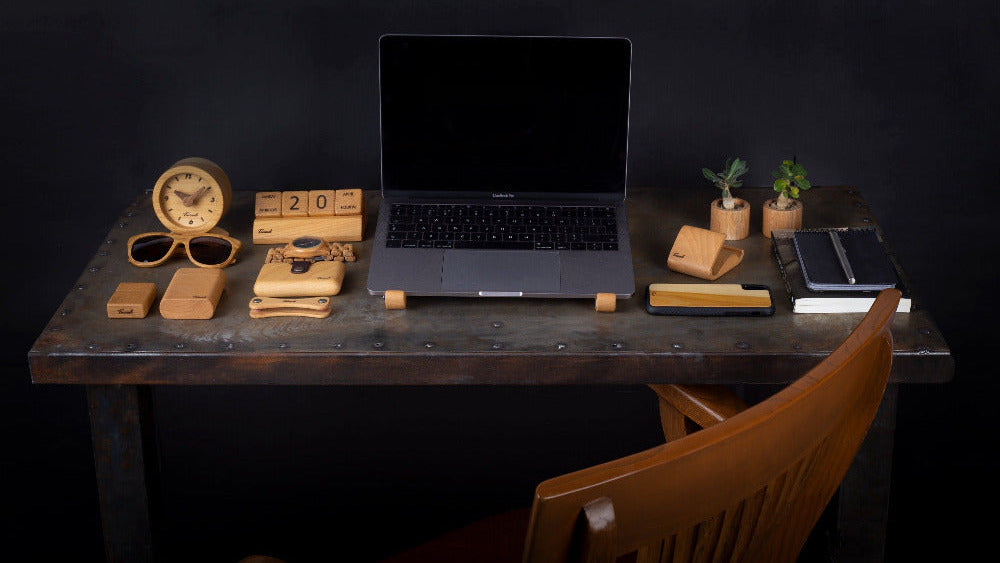 Dark wooden desk with laptop, office items, and a chair against a black background